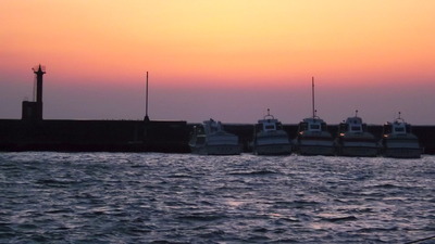 荒れる港沖　夕陽が艶やかー